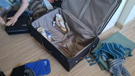 Half-packed suitcase on the floor surrounded by clothes