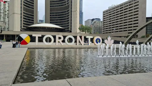 The letters of Toronto behind a fountain lake.