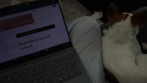 Laptop on lap beside a small dog lying down.