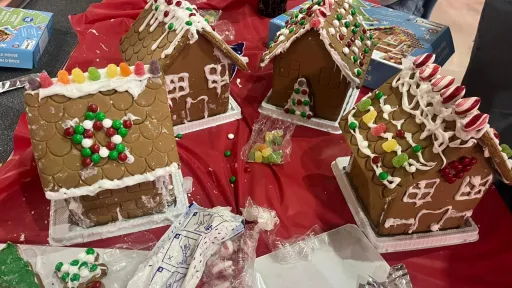 Gingerbread houses decorated with candy on a red tablecloth.