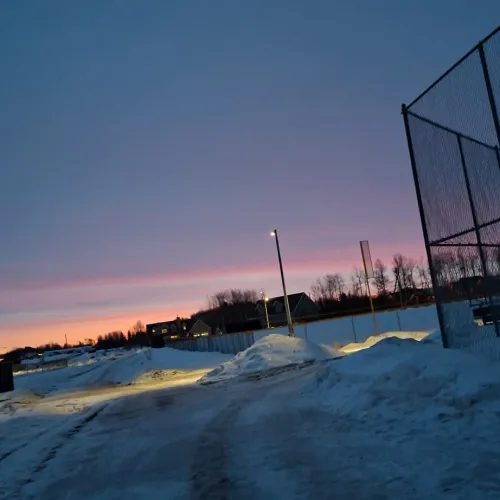 Snowy pathway at sunset with a dark sky and faint pink horizon.