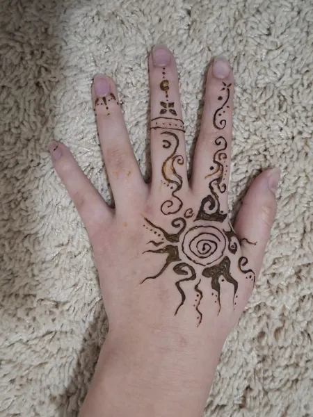 Henna design of sun and patterns on a hand with colorful bracelet.