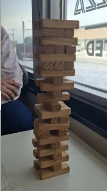 A tower of jenga in front a window from inside a cafe
