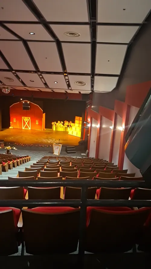 Empty theater with red seats and a lit stage in warm colors.