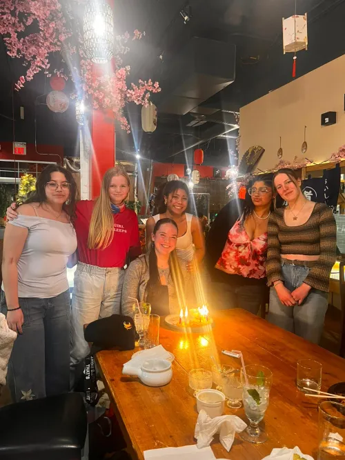 Group of six people smiling around a table with candles in a dimly lit restaurant.