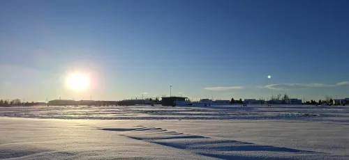 Sunset over snowy field with clear blue sky.