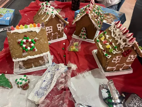 Gingerbread houses decorated with candy on a red tablecloth.