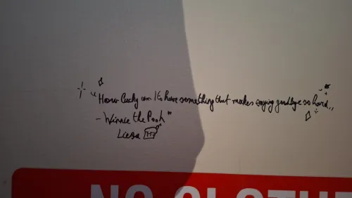 Quote handwritten on a wall above a partial sign.