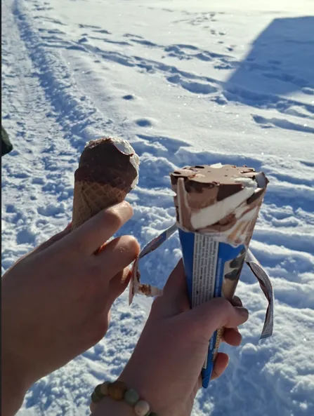 Two hands holding ice cream against a snowy background