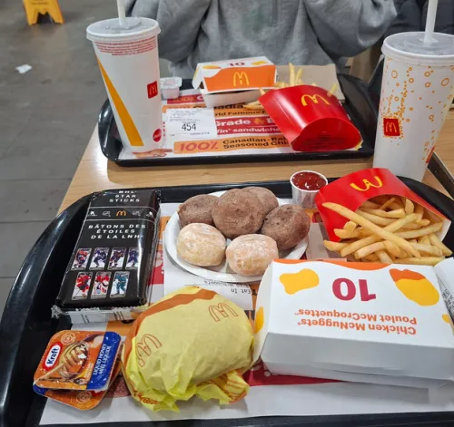 McDonalds meal on trays with burgers, fries, drinks, chicken nuggets, Mc pops and sauce.