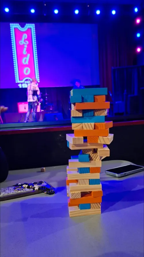 Colorful Jenga tower on a table in front of a stage with purple lighting.