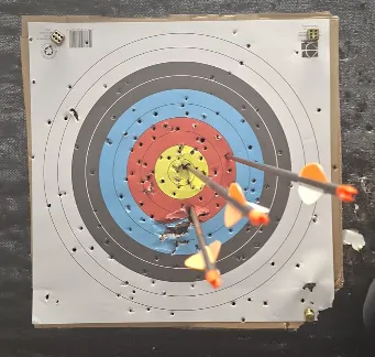 Three arrows hit a colorful target board, close to the bullseye.